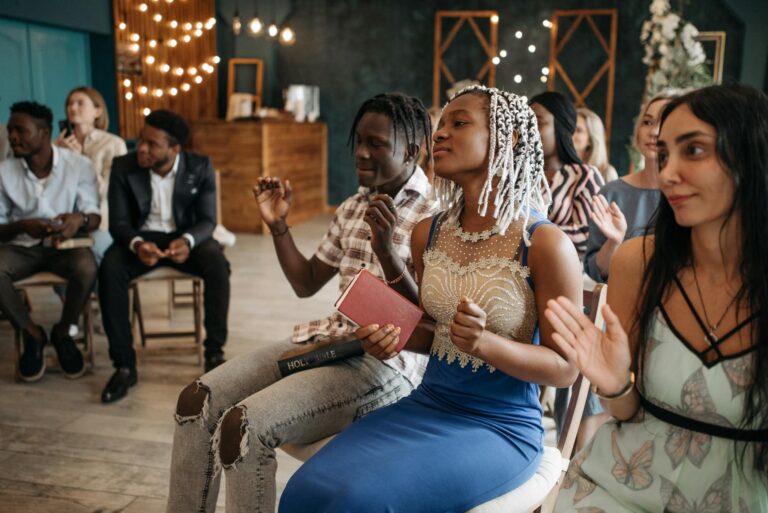 A diverse group of adults engaged in joyful prayer and worship indoors, expressing unity and faith.