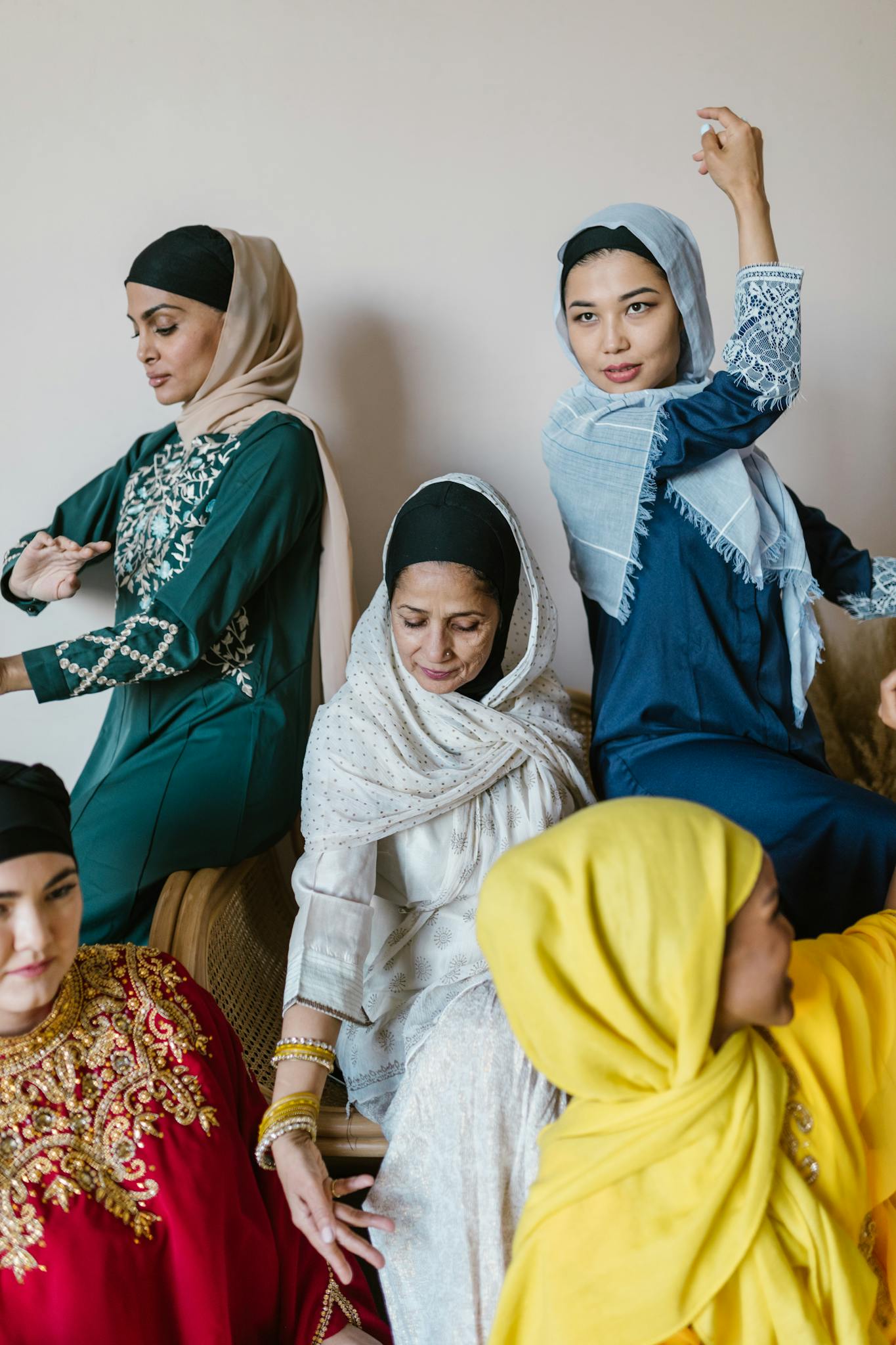A diverse group of women in colorful traditional clothing, sharing a moment of celebration indoors.