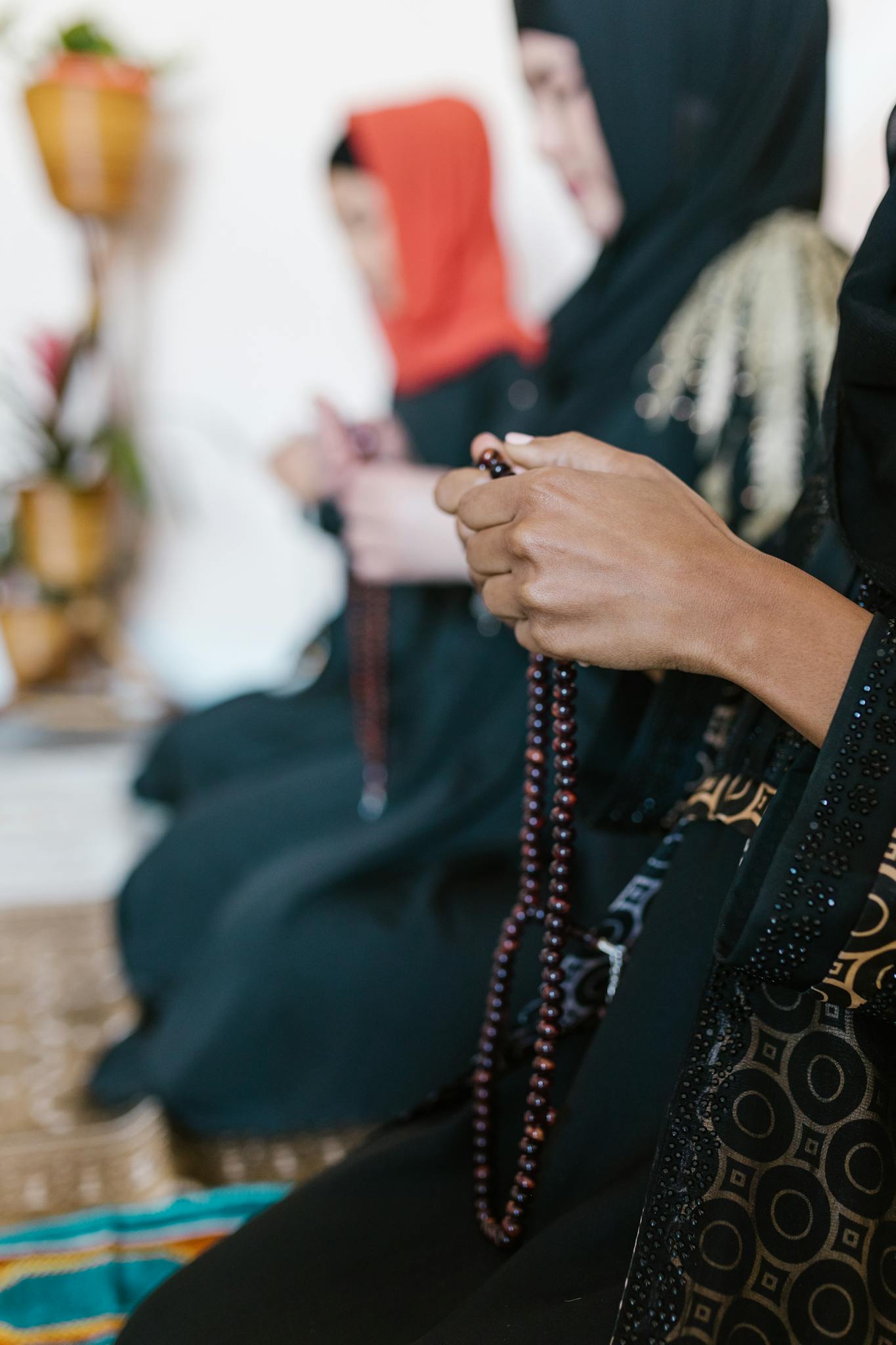 Women in hijabs praying with prayer beads, showcasing Islamic devotion and spirituality.